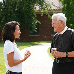 Le Moyne Student Conversing with Priest