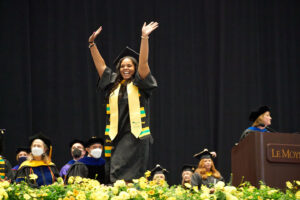 Student celebrating at graduation after getting supportive financial aid help.